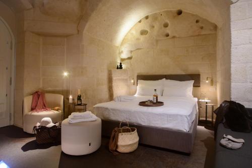 馬泰拉的住宿－Le Malve Cave Retreat，一间卧室配有一张大床和一把椅子