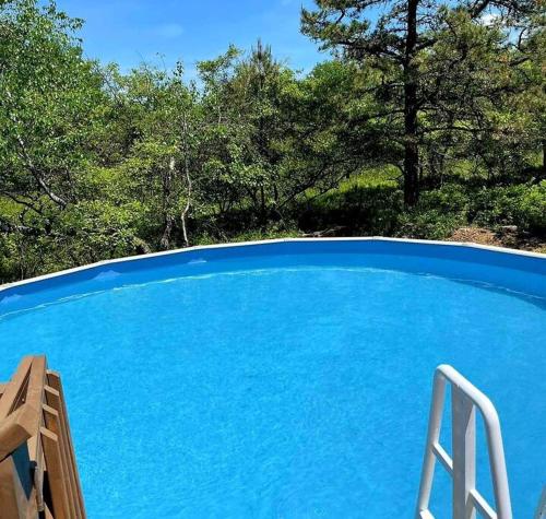 a large blue swimming pool with a chair next to it at Quiet Private House w Hot Tub/Fire pit/Games in Blakeslee