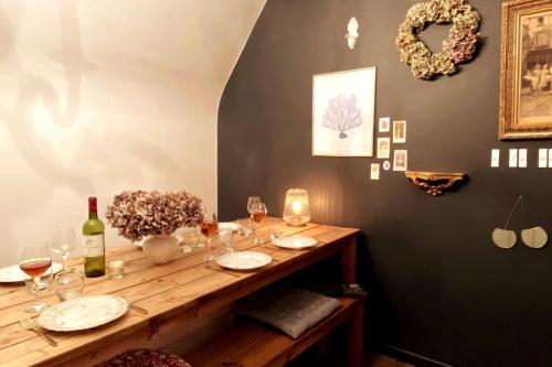 a wooden table with glasses and wine bottles on it at Grand appartement place Saint-Pierre, proche Château de Saumur et bord de Loire" in Saumur