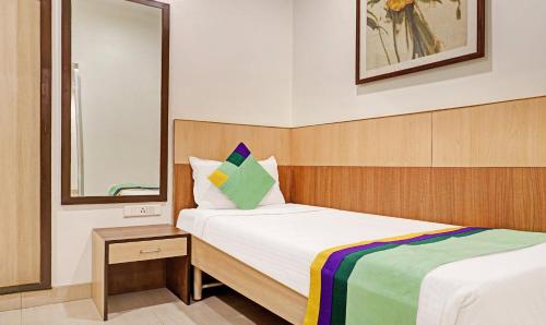 a small bedroom with a bed and a mirror at Hotel Madhav International Pune Railway Station in Pune