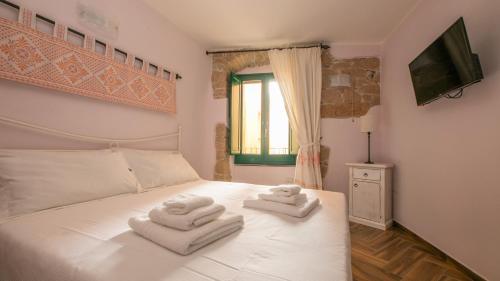 una camera da letto con due asciugamani su un letto bianco di Sardinian Gallery Fonte a Bosa