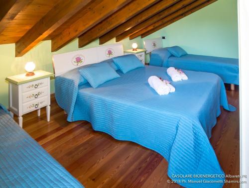 two blue beds in a room with wooden floors at Il Casolare Bioenergetico in Albareto