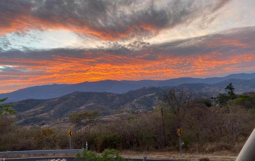 a sunset with a view of mountains and a road at Hotel SPA Campestre Los Adobes in Taxco de Alarcón