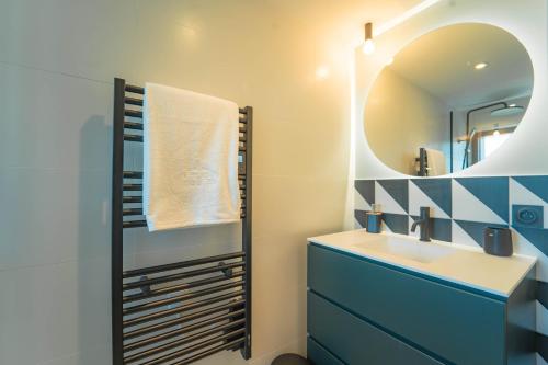 La salle de bains est pourvue d'un lavabo bleu et d'un miroir. dans l'établissement Villa Ananda - Gâia - Harmonie avec vue mer et étangs, à Carnon-Plage