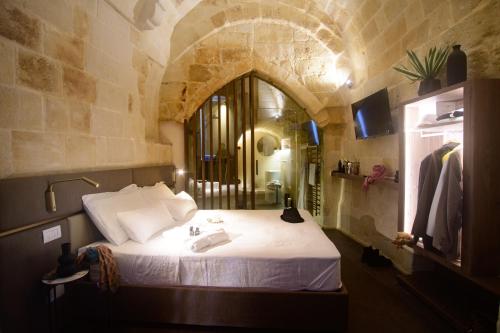 a bedroom with a large bed in a stone wall at Le Malve Cave Retreat in Matera