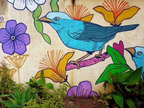 a painting of two birds on a wall with flowers at Villa Ágape - Chapada dos Veadeiros in Alto Paraíso de Goiás