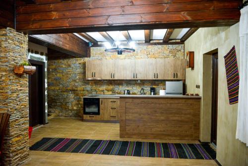 a kitchen with wooden cabinets and a brick wall at Къщи за гости НЕСИ in Leshten