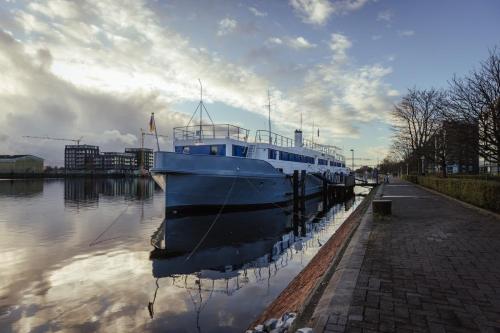 een blauwe boot is aangemeerd in het water bij ARCONA - Übernachten auf dem Wasser - direkt am Bontekai in Wilhelmshaven