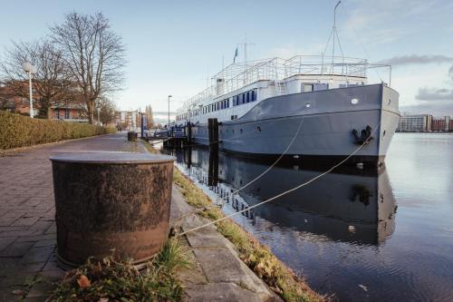 a boat docked in the water next to a sidewalk at ARCONA - Übernachten auf dem Wasser - direkt am Bontekai in Wilhelmshaven