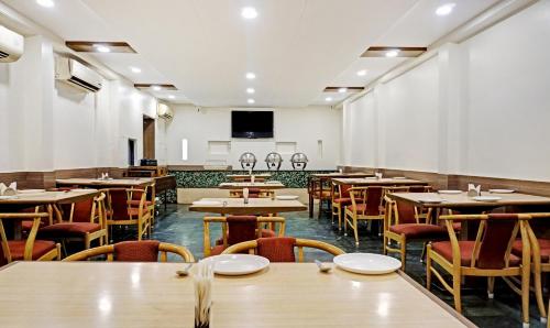 a restaurant with tables and chairs and a flat screen tv at Hotel Madhav International Pune Railway Station in Pune