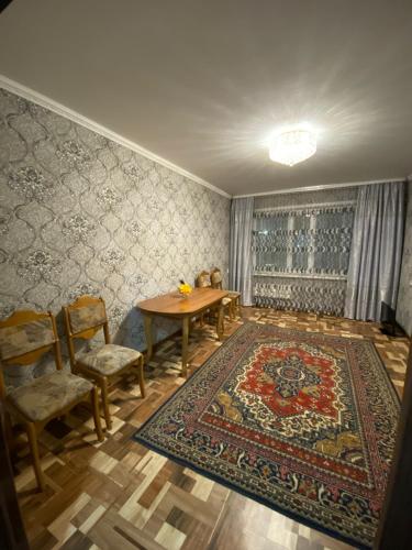 a dining room with a table and chairs and a rug at Сдам квартиры посуточно in Kokshetau