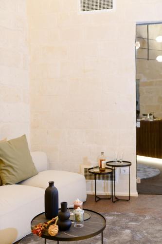 a living room with a white couch and two tables at Le Malve Cave Retreat in Matera