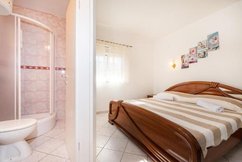 een slaapkamer met een bed en een badkamer met een toilet bij Bistra Pakoštane Apartments in Pakoštane