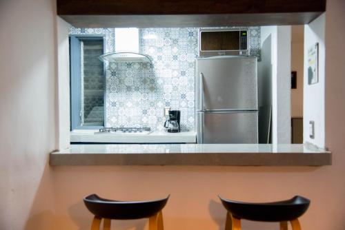 a kitchen with a refrigerator and two stools at Departamento Glorieta La Normal in Guadalajara