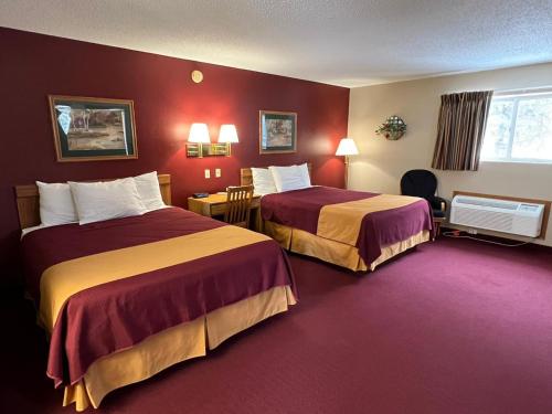 duas camas num quarto de hotel com paredes vermelhas em Americas Best Value Inn Suburban em Emmetsburg