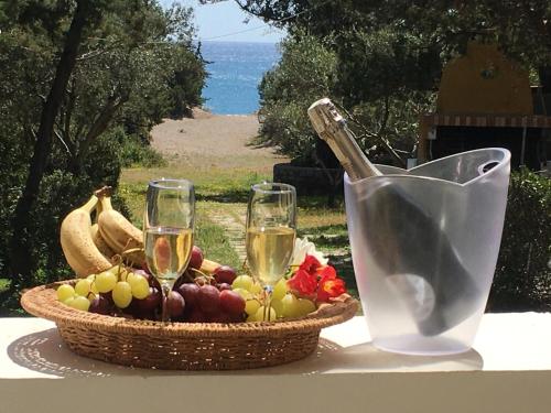 ein Obstkorb und zwei Gläser Wein auf einem Tisch in der Unterkunft Beachfront Villa SeaShell Superior in Gennadi