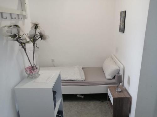 ein kleines Bett in einem Zimmer mit einer Vase auf einem Tisch in der Unterkunft Wohnung in Köln 1B in Köln