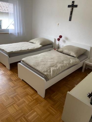 two beds in a room with a cross on the wall at MaRe FeWo in Hettingen