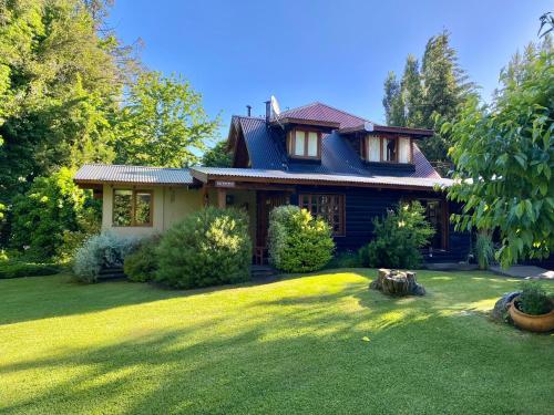 una casa con un gran césped delante de ella en Altos del Sur Cabañas de Montaña, en El Bolsón