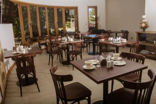 um restaurante com mesas e cadeiras de madeira e janelas em Cocurantu Hotel Boutique em Pucón