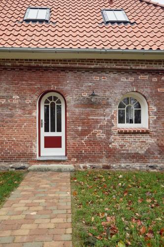 a brick house with a white door and two windows at Gemütliches Ferienhaus - Kornlager in Barkelsby