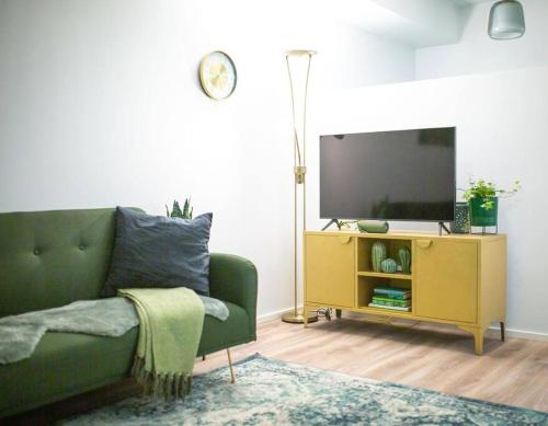 a living room with a green couch and a tv at New studio apartment with free parking in Kuopio