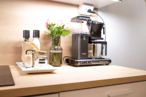 New studio apartment with free parking في كوبيو: طاولة مطبخ مع آلة صنع القهوة والزهور
