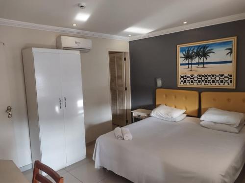 Un dormitorio con una cama blanca y una pintura en la pared en Lemes Hotel, en Barra do Piraí