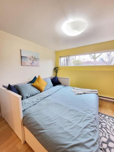 1 dormitorio con cama con sábanas azules y ventana en Sunshine Suite en Vancouver