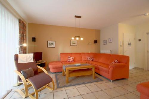 ein Wohnzimmer mit einem orangenen Sofa und einem Tisch in der Unterkunft DW10a FeWo Diekkieker in Spieka-Neufeld