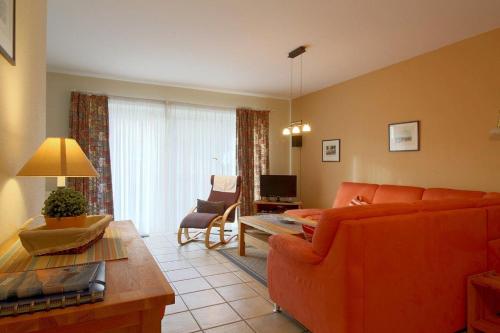 a living room with an orange couch and a table at DW10a FeWo Diekkieker in Spieka-Neufeld