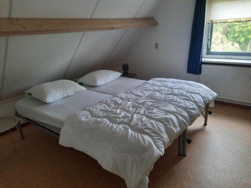 a bedroom with a large bed with white sheets and pillows at Waterhuis Friesland in Oudwoude