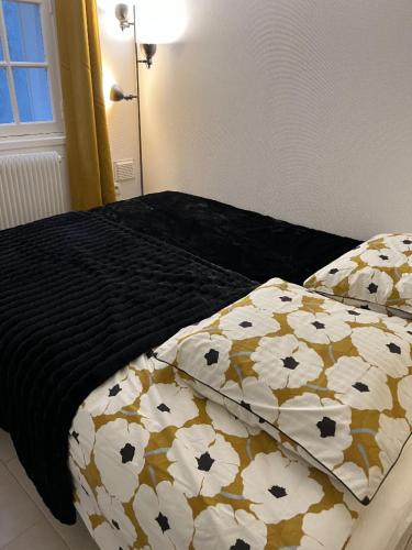 - un lit avec une couverture noire et des oreillers dans l'établissement Destination Versailles, à Versailles