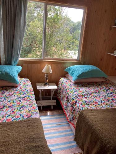 1 dormitorio con 2 camas y ventana en Cabañas encanto del bosque, en Castro
