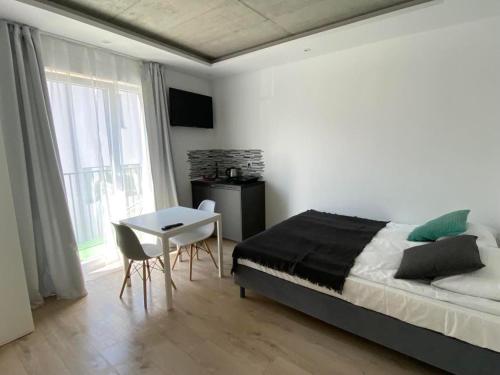Schlafzimmer mit einem Bett, einem Tisch und einem Fenster in der Unterkunft BLOMMA Niechorze in Niechorze