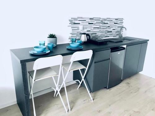 a kitchen with a black counter with two stools at BLOMMA Niechorze in Niechorze