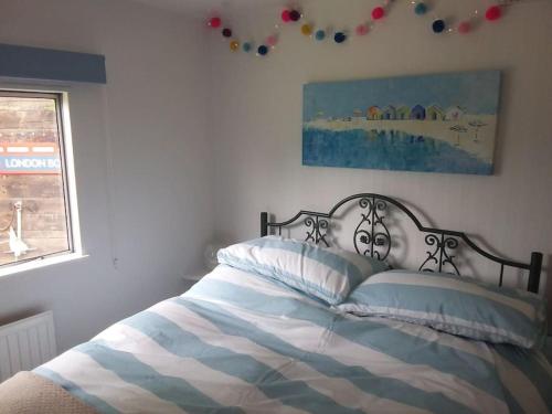a bed with a blue and white blanket and a window at Rockets's Retreat in Bursledon
