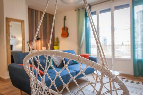 - une balançoire dans le salon doté d'un canapé bleu dans l'établissement Paul Janet, à Grenoble