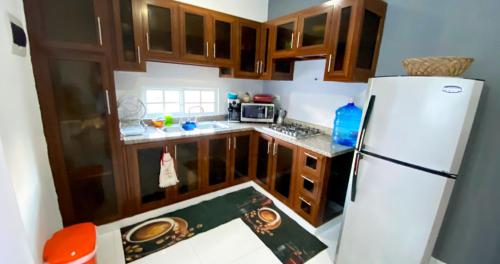 a kitchen with a white refrigerator and wooden cabinets at Cozy 2BR Near Playa Dorada, 3 Min In Car in San Felipe de Puerto Plata