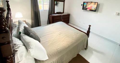 a bedroom with a bed with white sheets and pillows at Cozy 2BR Near Playa Dorada, 3 Min In Car in San Felipe de Puerto Plata