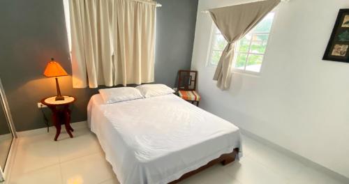 um quarto com uma cama branca e uma janela em Cozy 2BR Near Playa Dorada, 3 Min In Car em San Felipe de Puerto Plata