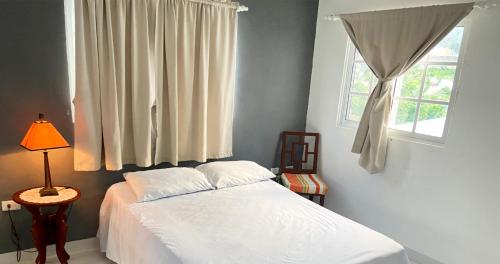 a bedroom with a white bed and a window at Cozy 2BR Near Playa Dorada, 3 Min In Car in San Felipe de Puerto Plata