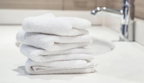 a stack of white towels sitting on a bathroom sink at Island Inn & Suites, Ascend Hotel Collection in Piney Point