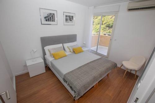 une chambre avec un lit avec des oreillers jaunes et une fenêtre dans l'établissement Penthouse Exceptionnel vue Mer proche Monaco, à Beausoleil
