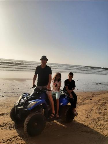 a man and two children sitting on a quad bike on the beach at Dar diafa samira in Mirleft