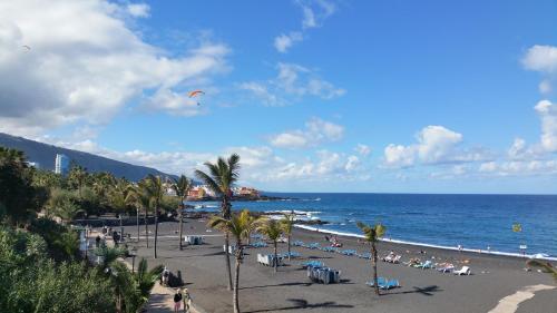 a beach with people on the sand and the ocean at Hotel Tropical in Puerto de la Cruz