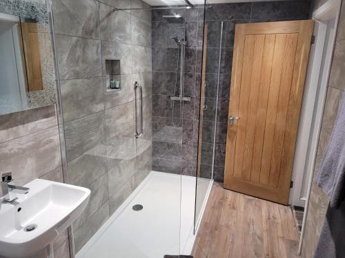 a bathroom with a shower with a sink and a glass door at Fountain Cottage Cafe and B&B in Bellingham