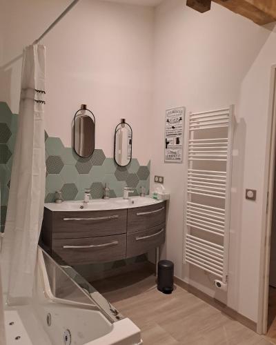 a bathroom with a tub and a sink and mirror at Domaine Ecoline in Sadirac