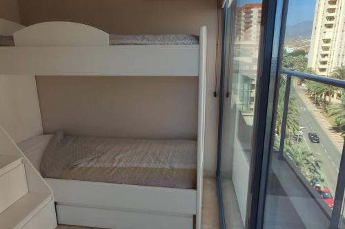 um pequeno quarto com uma cama e uma janela em Espectacular Ático con excelentes vistas. em Almeria