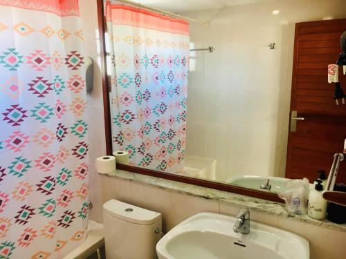 a bathroom with a toilet and a sink and a mirror at La Casita di Fuerte in Caleta De Fuste